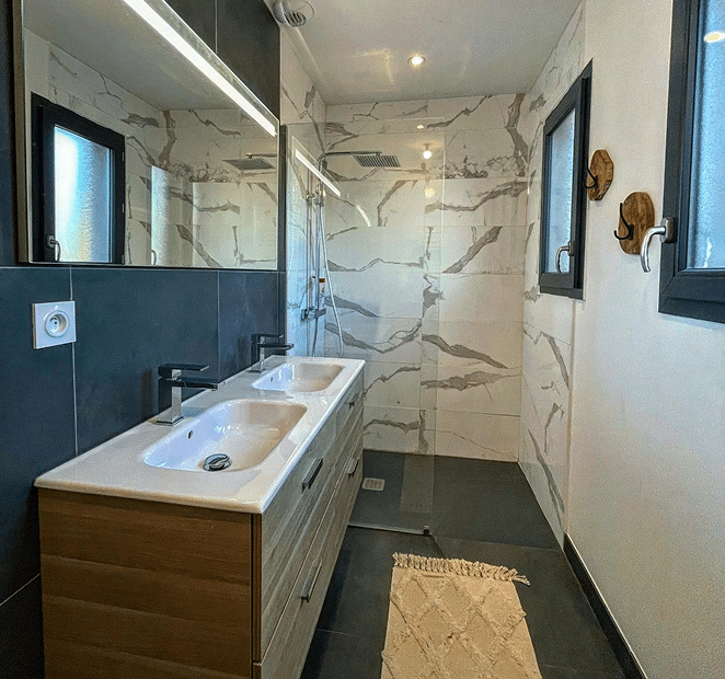 Salle de bain moderne équipée de vasques en bois et cloisons hydrofuges résistantes à l'humidité.